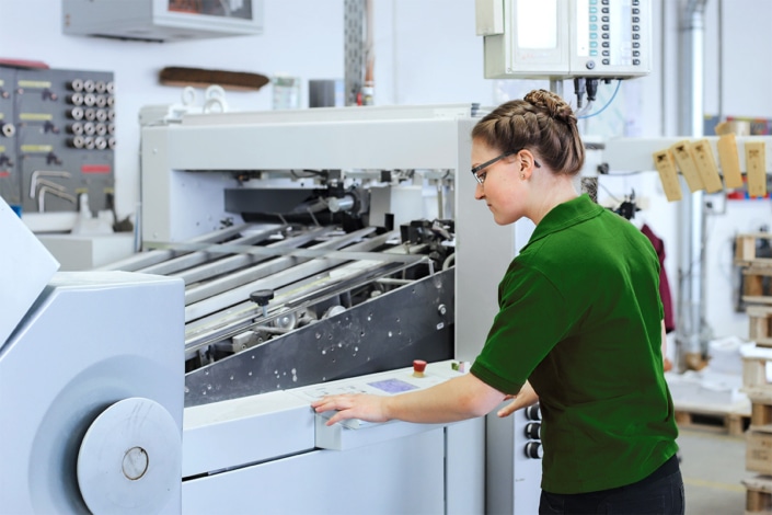 Junge Frau arbeitet an einer großen Druckmaschine